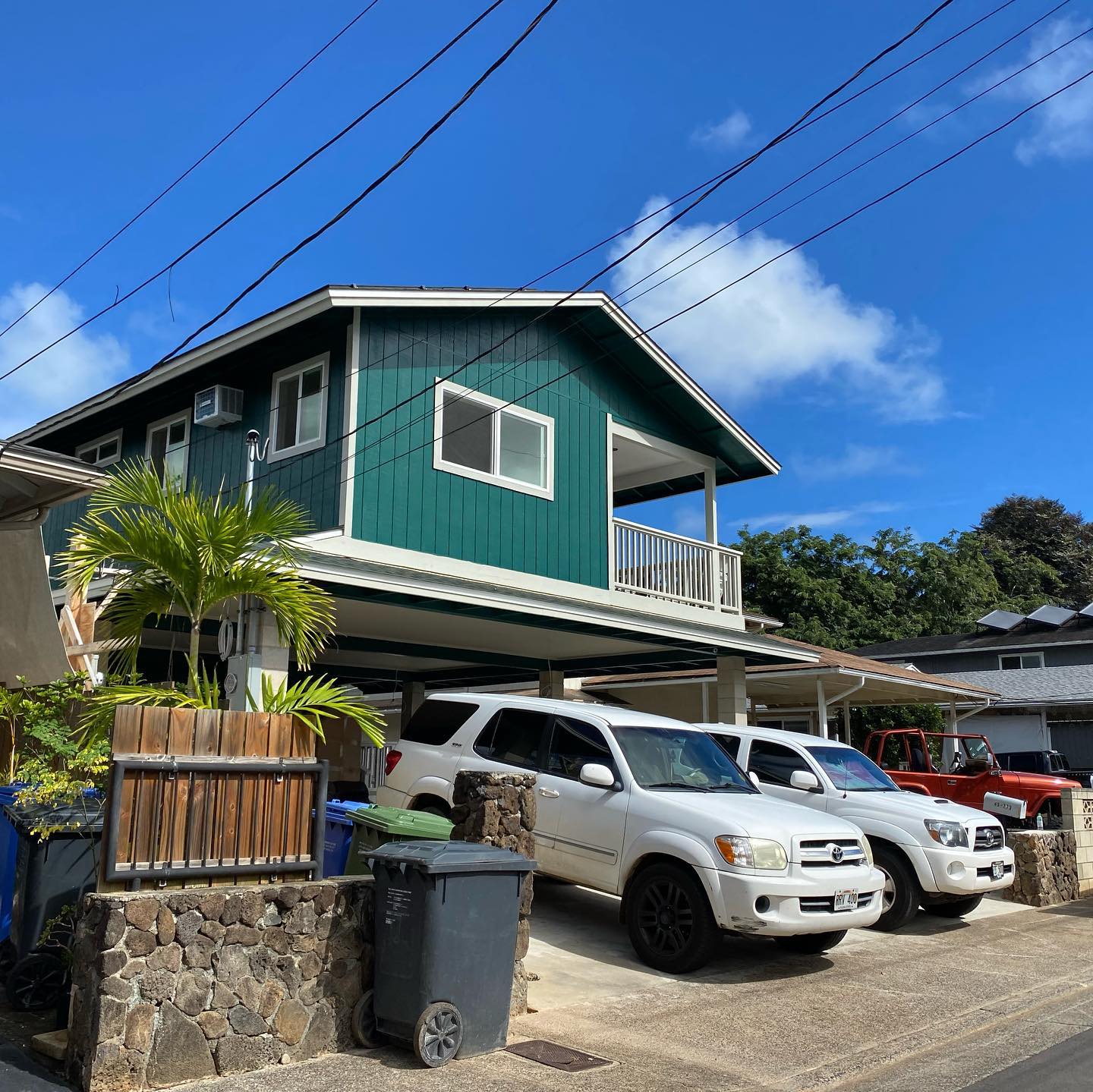 Deep teal two-story plantation home with white trim and lanai