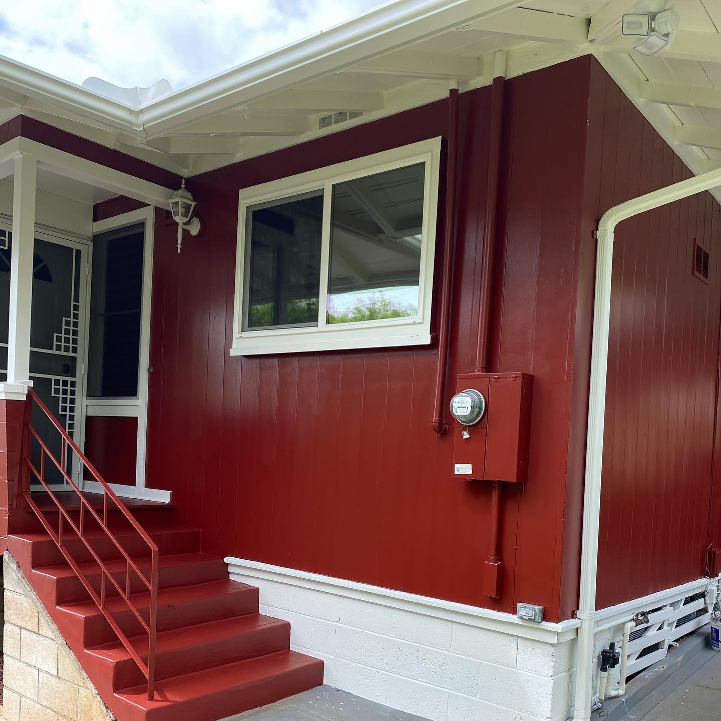 Deep red cottage exterior with white trim and railing