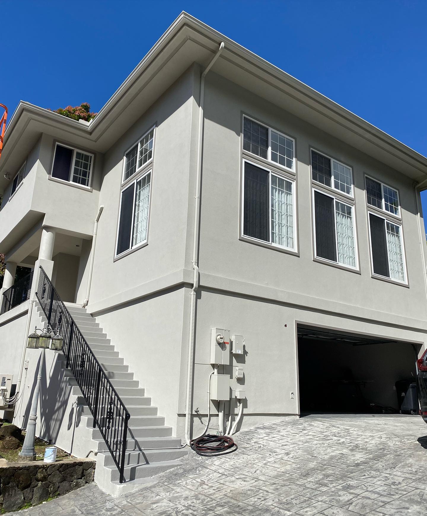 Two-story grey stucco home repaint with stair entry
